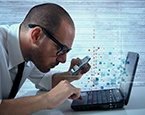 Man using a magnifying glass to inspect laptop