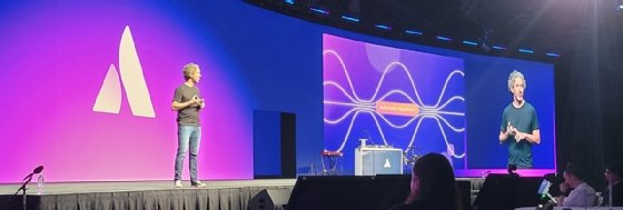 Image of Scott Farquhar on a large stage with the presentation on a large screen