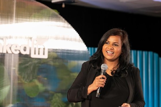 A woman smiles while speaking into a microphone on stage at LinkedIn.