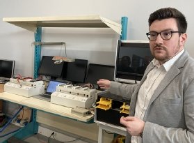 Photo de Cédric Fourgous devant des bancs de test de disques durs